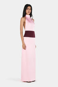 Model wearing the Venetia Maxi Dress in Wine Pink, featuring a soft pink satin halter neckline, contrasting burgundy waistband, open-back design and elegant floor-length column silhouette, against a light grey studio background.