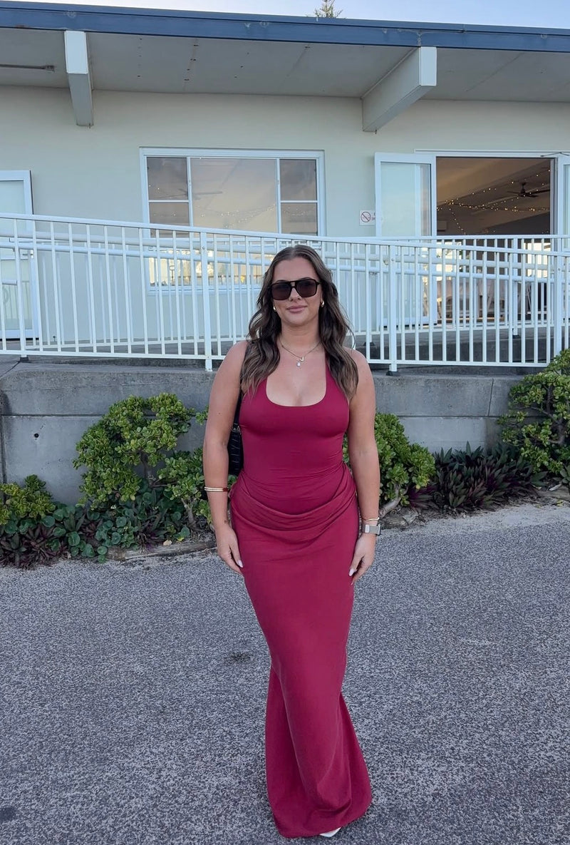 Woman in a red dress standing in front of a house with a white railing. - @jessmeyerman
