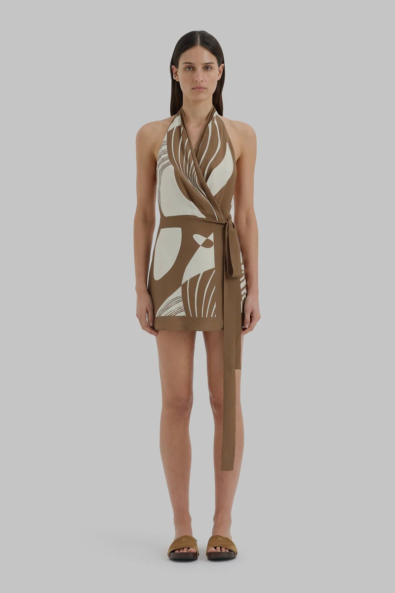 Woman wearing a sleeveless dress with a geometric pattern on a plain background