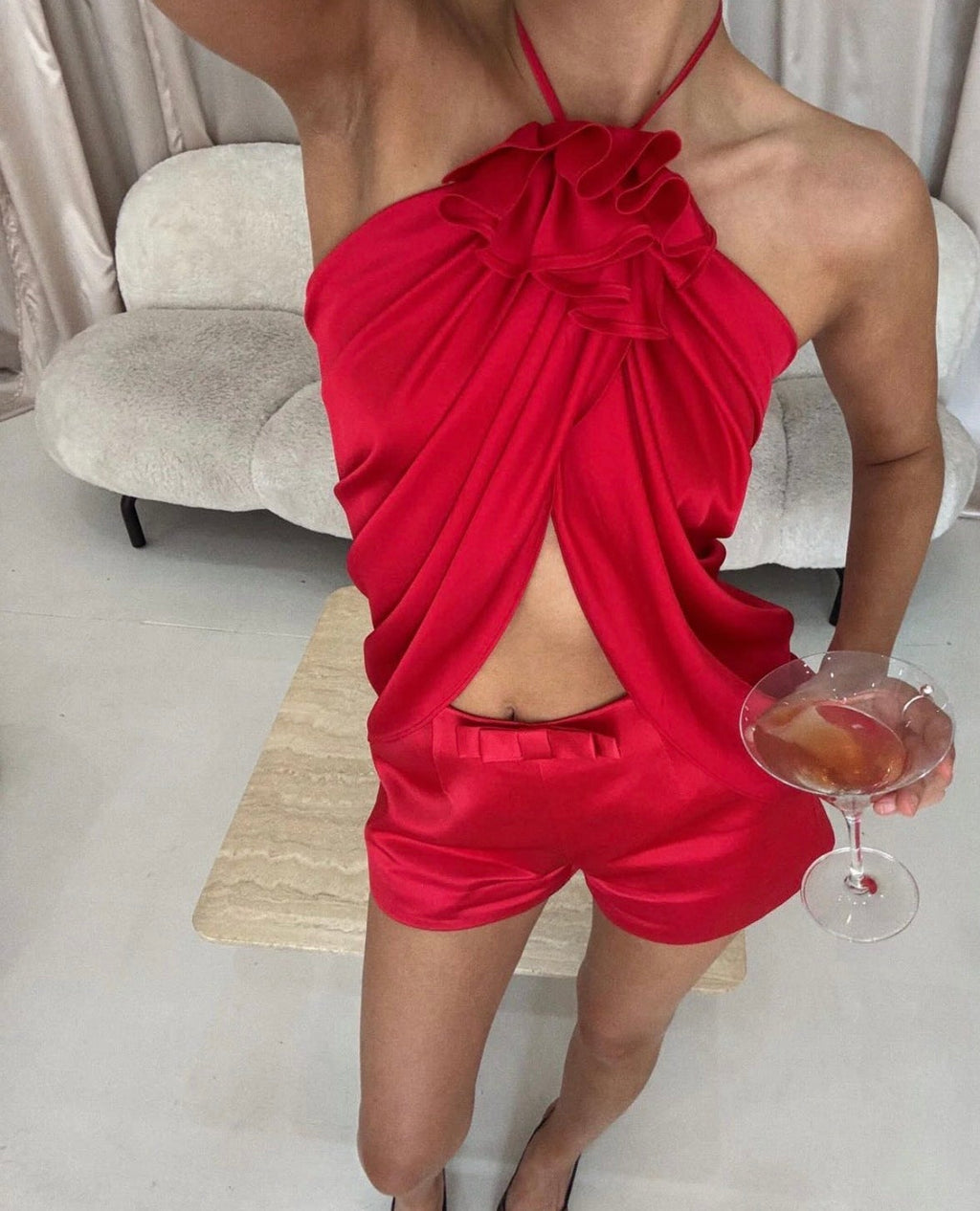 Person wearing a red outfit holding a cocktail in a minimal indoor setting