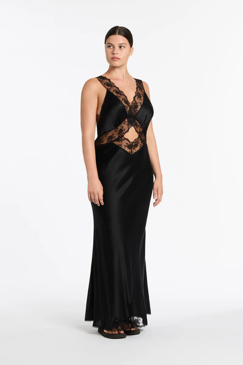 Woman wearing a black evening gown with lace detailing on a white background