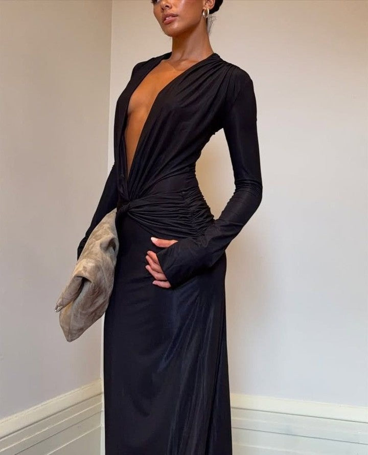 Woman wearing a black dress with long sleeves against a plain background