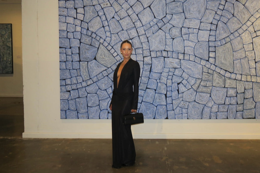 Woman in a black dress standing in front of a large abstract wall art piece.