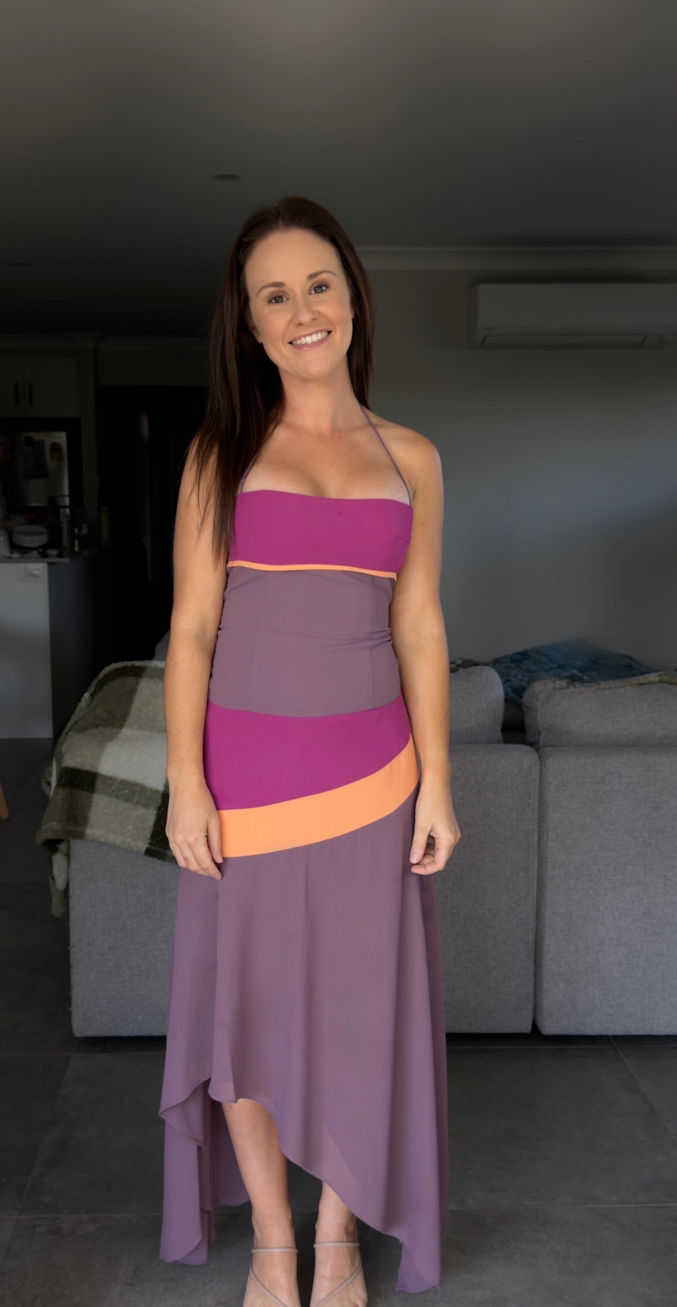 Woman wearing a two-tone dress standing in a living room.