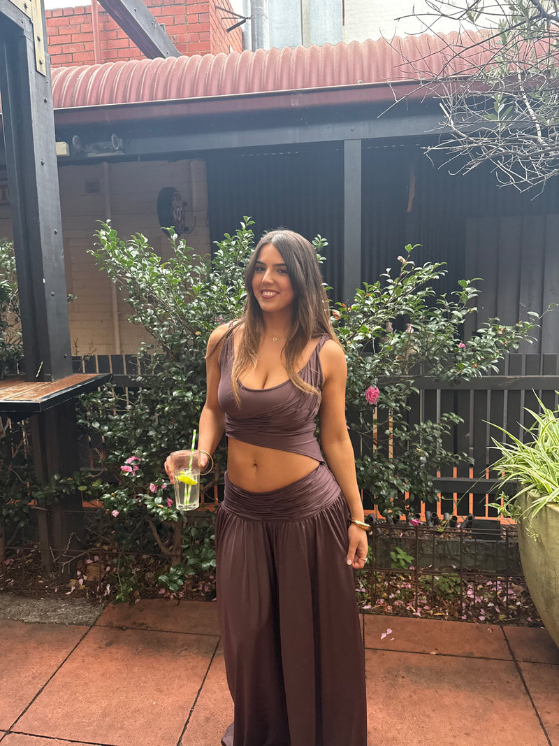 women in a brown set standing in the outdoors with a glass in her hand. - @jessdademo