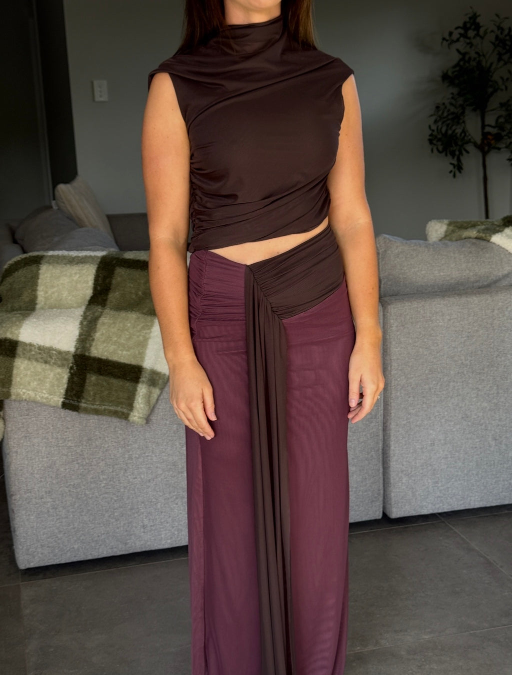 Person wearing a brown top and purple pants in a living room setting