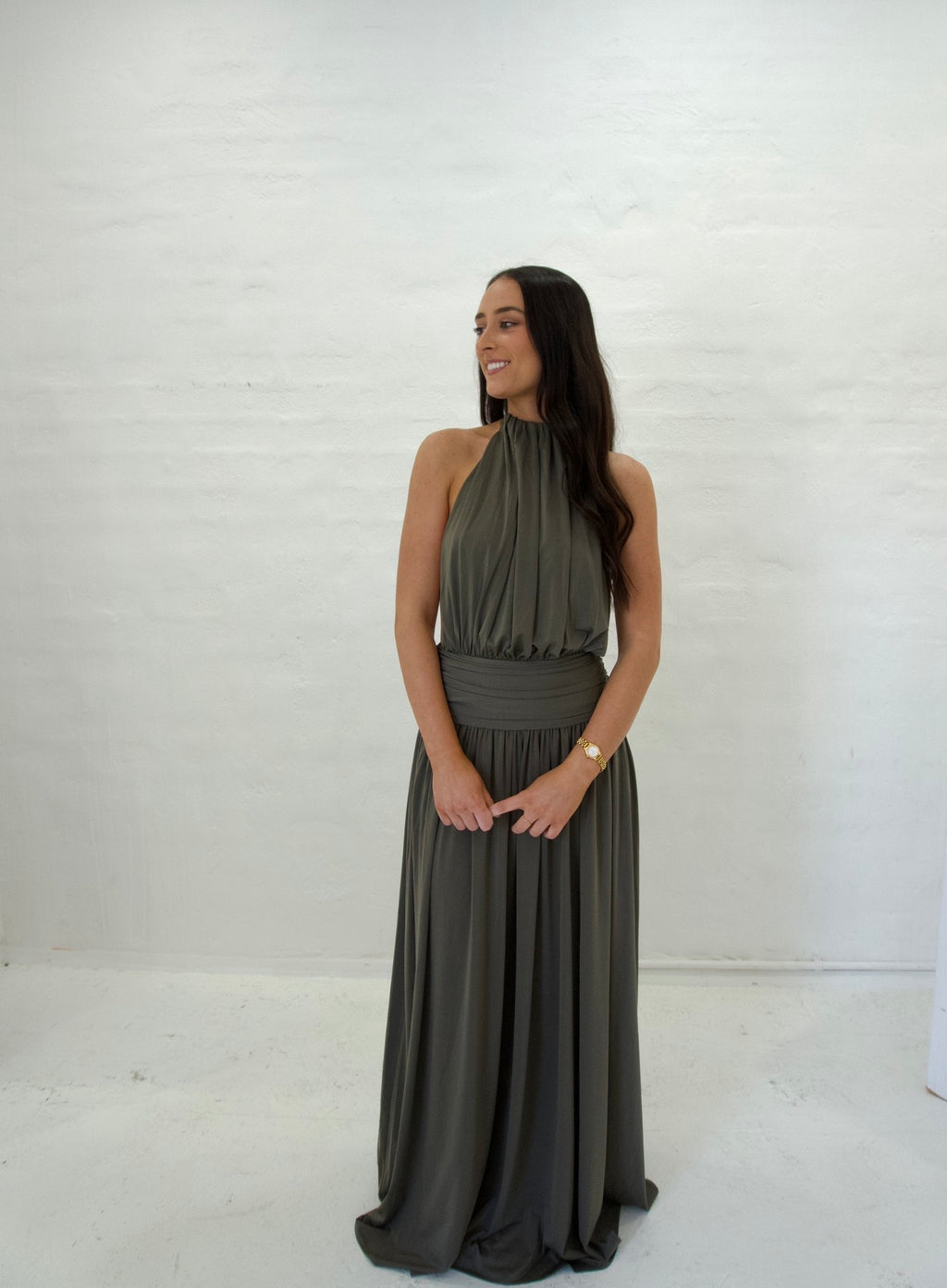 Woman wearing a long dark green dress against a white background