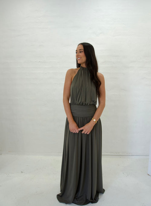 Woman wearing a long dark green dress against a white background