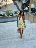 Woman in a yellow dress walking on a stone staircase with a fountain in the background.