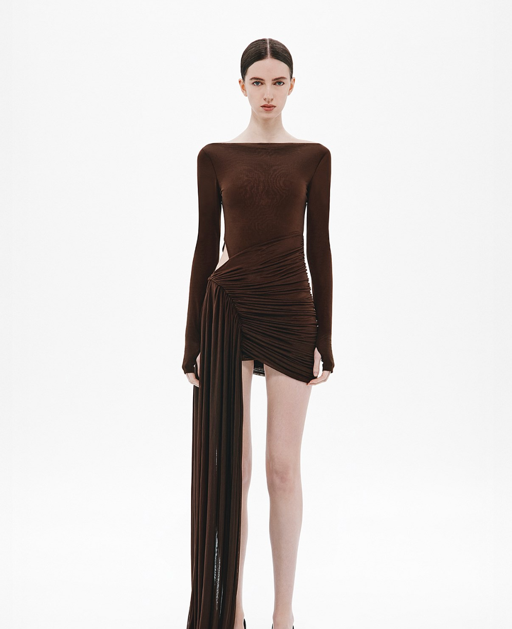 Woman wearing a brown dress with long sleeves and a draped skirt on a white background