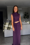 Woman in a purple dress standing in a living room.