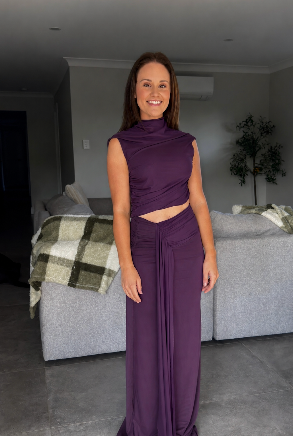 Woman in a purple dress standing in a living room.