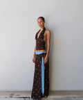 Woman wearing a brown and blue polka dot outfit against a white wall.