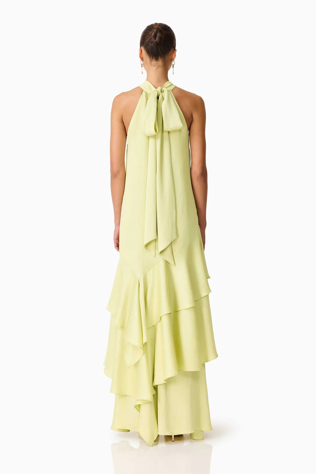 Women from behind standing in front of a white backdrop in a green tie maxi dress